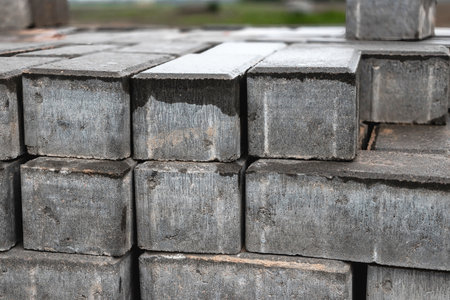 Gray cinder blocks are neatly stacked at a construction site, ready for use in building projects under bright daylight.の写真素材