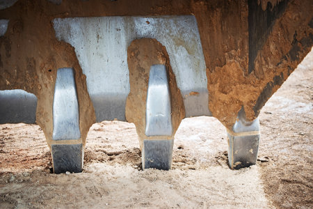 The powerful digging arm of a excavator is positioned above the ground, ready to break earth at a...