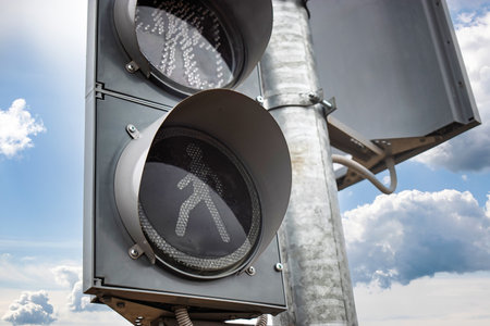 A traffic signal illuminates the pedestrian walk symbol, guiding people safely across a busy...