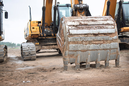 Excavators stand ready at a construction site, designed for earthmoving tasks. Heavy machinery is...