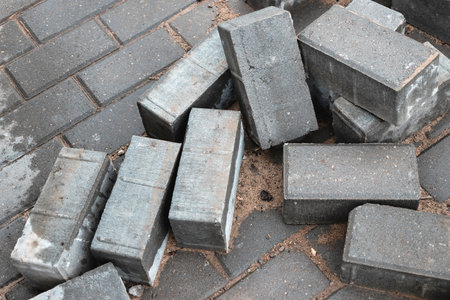 Gray bricks are scattered on a cobblestone pavement, showing the ongoing construction process in a busy city environment.の写真素材