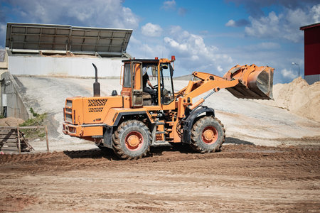 A loader is seen at a construction site, moving dirt and materials under a clear blue sky....