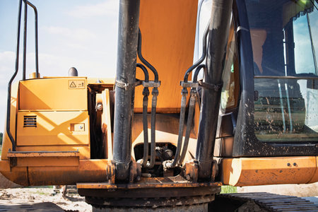 A large excavator is actively working at a construction site, showing its hydraulic systems under clear skies. Dust is visible in the air as the machine moves.の写真素材