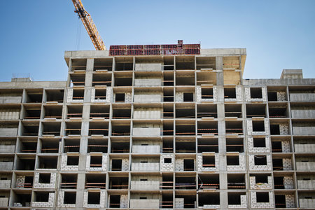 Workers continue the construction of a high-rise building in an urban setting, showing concrete...