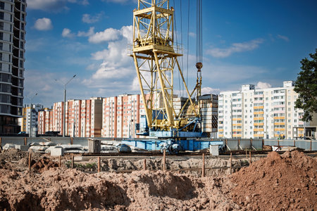 A yellow crane towers over an active construction site surrounded by newly built residential buildings, showing urban development in progress.の写真素材