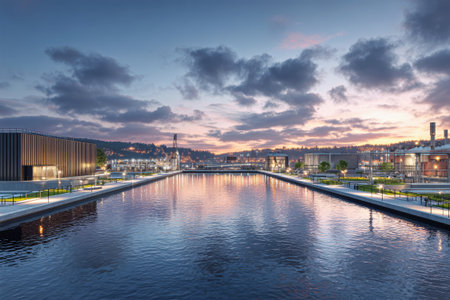 A stunning urban water treatment facility reflects vibrant sunset hues on a tranquil river, framed by an intricate cityscape and enhanced by modern architecture.の素材