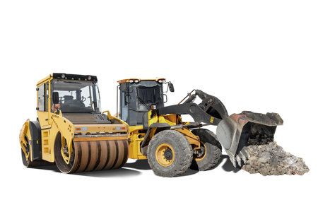 Two large construction machines, a wheel loader and a road roller, are positioned together in an...