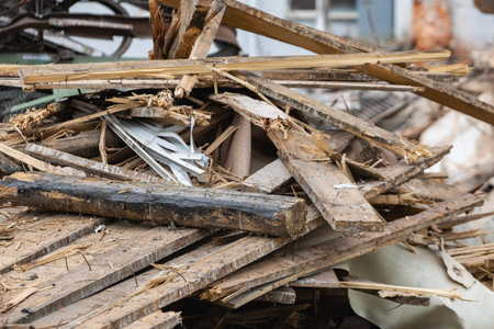 Construction workers dismantle a building, leaving a large pile of wood and debris at the site. The area shows signs of heavy machinery and ongoing work.の写真素材
