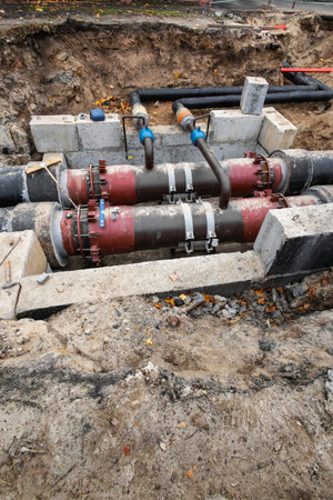 Workers are performing maintenance on underground utility pipes at a construction site. The area...