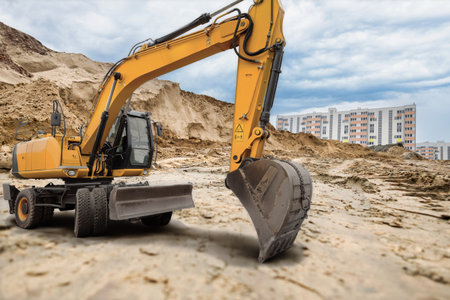 Heavy excavator works diligently at a construction site, moving earth and preparing the land while...