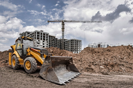 Heavy machinery operates on a construction site with cranes and unfinished buildings in the...