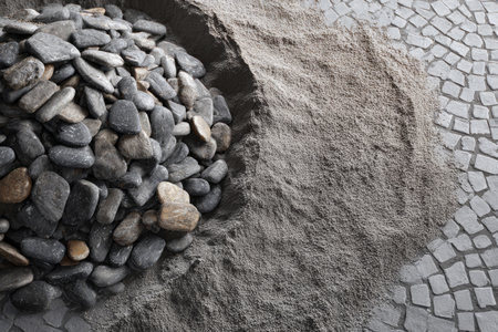 Cobblestones and sand create a base for pavilion construction, highlighting the ongoing process of laying a new sidewalk and patio area with crafting precision.の素材