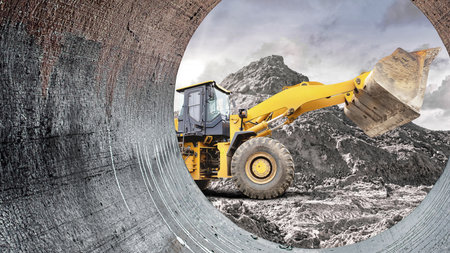 Heavy machinery is seen digging and moving earth at a construction site. The view is framed by a...