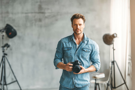 A man stands confidently in a modern studio filled with soft natural light, holding a camera and ready to capture artistic moments of inspiration.の素材