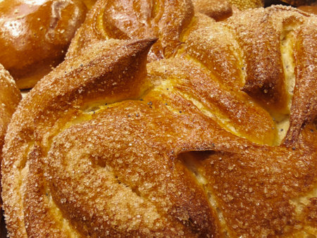 Fresh sweet bread sits on display in a bakery. The golden crust shines under warm lights as the...