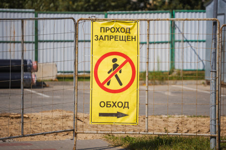 A sign shows a no entry symbol and instructions a detour to avoid a blocked pathway at a construction site in an urban area during the day.の写真素材