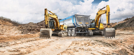 Construction activity is ongoing on dry, cracked earth where excavators are seen positioned beside a...