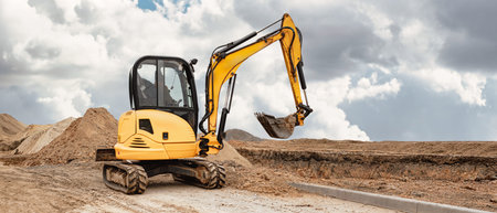 A mini excavator digs the earth, shaping the landscape at a busy construction site. Using compact...