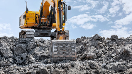 A large excavator operates diligently, moving mounds of gravel under the clear sky, showing the...