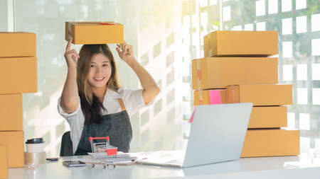 Young Asian working at home and starting a small business SME with online internet. And a laptop on...