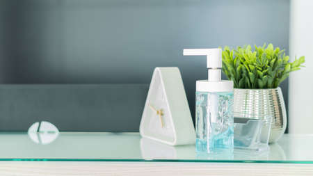 Bottles of hand sanitiser are placed on the table and plant cups with a clock in the background.の写真素材