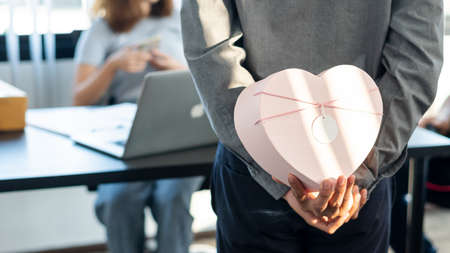 A young man hides a gift behind him to give to his girlfriend on Valentine's Day.の写真素材