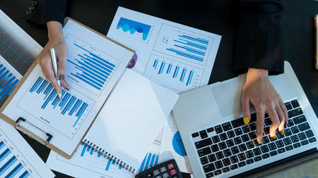 A young businessman who is calculating and analyzing graphs on a desk with a laptop with a top view.