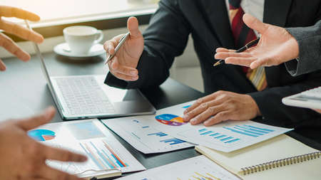 A businessman studying statistics and holding a graph document by hand An office worker stood near...
