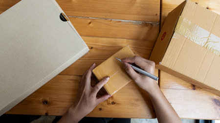 Small business owners start by writing address on cardboard boxes at work, entrepreneurs, small...
