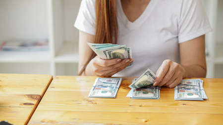 The dollar in the hand of the girl counted on the table with front viewの写真素材