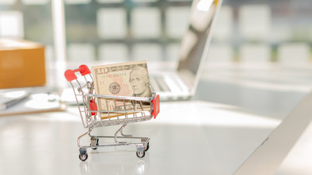 The dollar in the cart on the table on the table background with a laptopの写真素材