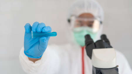 Hand test tube scientist or lab coat doctor working in biotechnology laboratory microscope equipment for clinical laboratory research front viewの写真素材