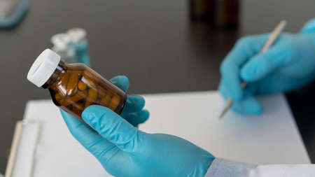 A medicine bottle in the hand of a doctor holding a doctor prescribing medicine to the patient the...