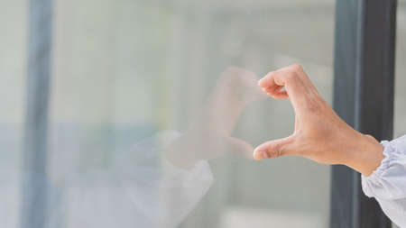 The young doctor's hand made a heart-shaped mirror with a reflection.の写真素材