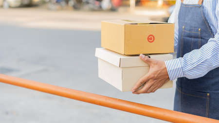 A young Asian deliveryman with a mailbox in a protective uniform, he provides service and the...