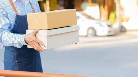 A young Asian deliveryman with a mailbox in a protective uniform, he provides service and the customer receives the front door.の写真素材