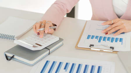 Young businesswoman analyzes cost graphs on desk in conference room with laptopの写真素材