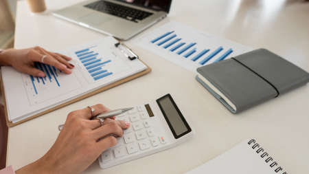 Young businesswoman analyzes cost graphs on desk in conference room with laptopの写真素材