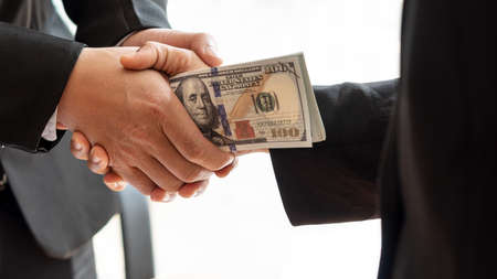 Close-up of two businessmen holding hands together and receiving banknotes in their hands, white...
