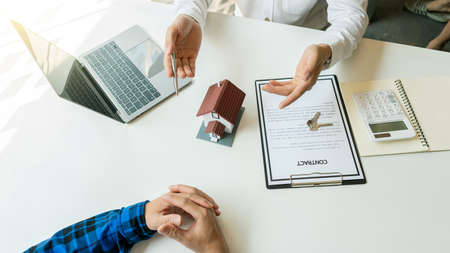 Businessmen and real estate agents introduce clients and negotiate home insurance purchase and sign contracts. Home insurance concept. And selling a home.の写真素材