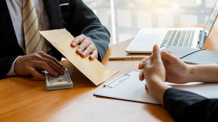 Businessman receives money and brown envelope proposed in file - office bribery and corruption ideas.の写真素材
