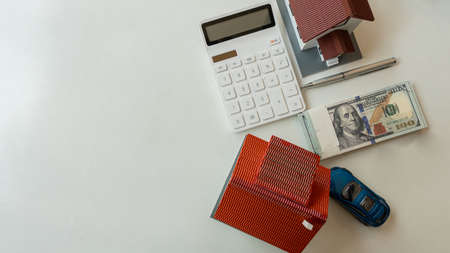 Home and car debt settlement ideas with dollar bills with white table top calculatorの写真素材