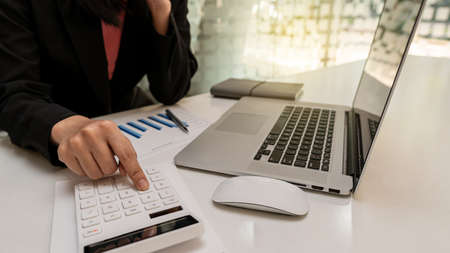 The businesswoman's hand presses the number machine, analyzing the graphs, showing the results of...