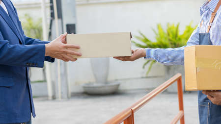 The courier holding the box in hand, the concept of sending and receivingの写真素材