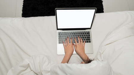 A beautiful Asian woman happy working on a laptop sitting in bed in the house.の写真素材