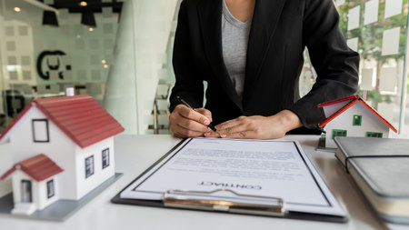 A real estate agent shows the house details in her file to clients who are looking for and...