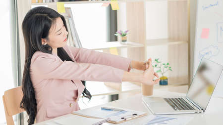 A beautiful Asian businesswoman works with documents, graphs, analyzes, and uses a laptop to work from home to create a social distance.の写真素材