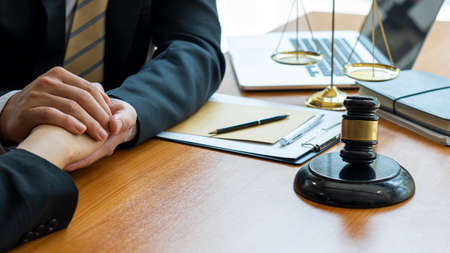 The judge hammer and the scales of a fair uncle on a table where a lawyer advises clients.