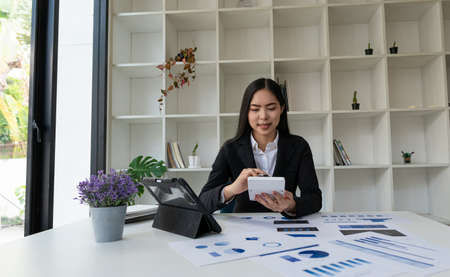 Asian businesswoman working on a laptop computer analyzing financial graphs on business issues...