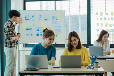 Two young Asian business women meet to analyze the financial chart at the office to discuss the...